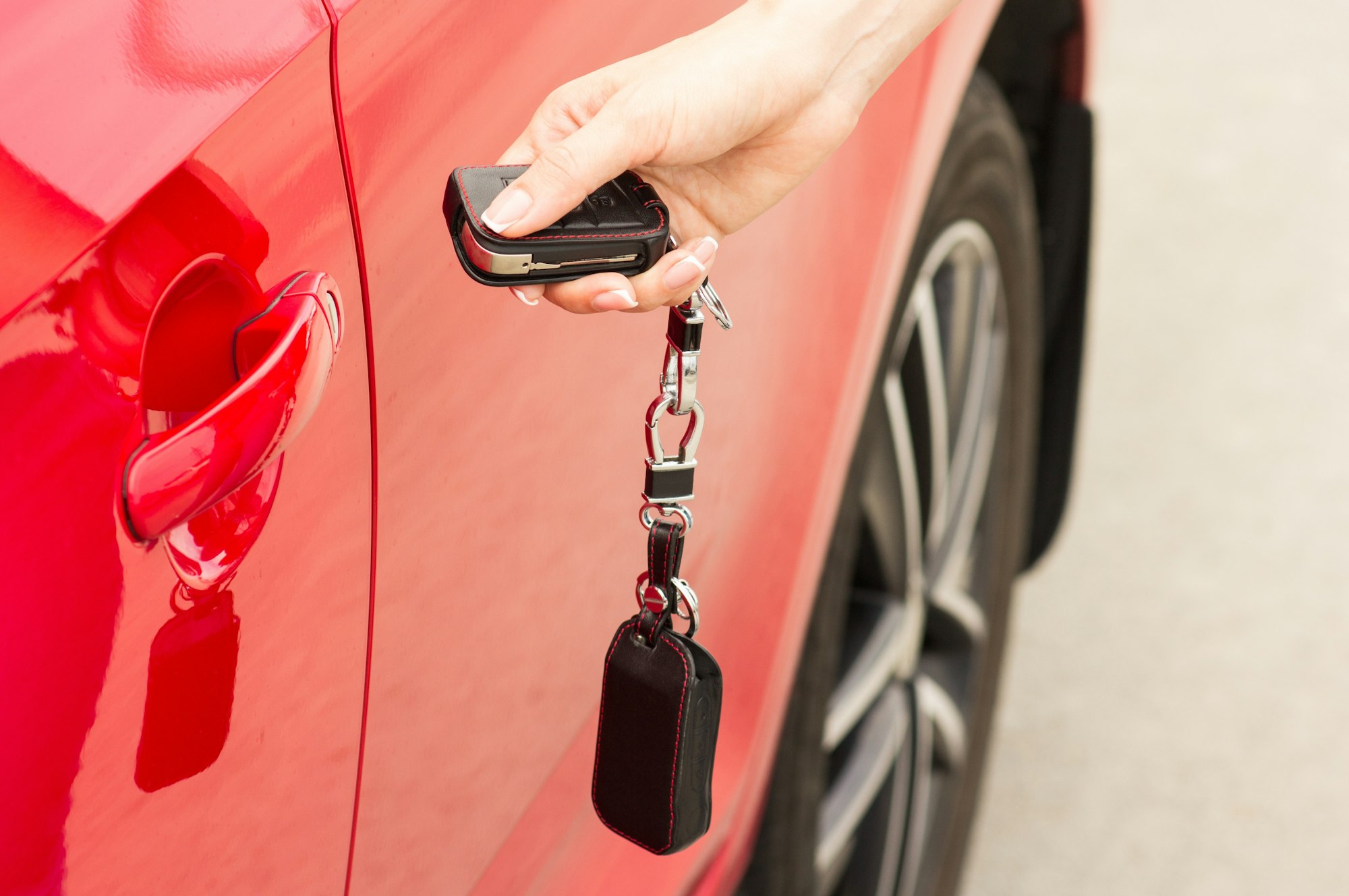 Female hand opens the door of a red car